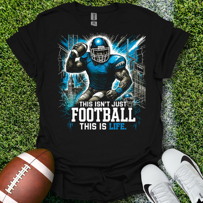 Black t-shirt with football player graphic and text 'This isn't just football, this is life' on grass with a football and shoes.