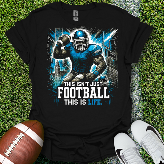 Black t-shirt with football player graphic and text 'This isn't just football, this is life' on grass with a football and shoes.