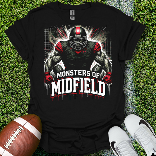 Black t-shirt with football player graphic and 'Monsters of Midfield' text on grass with a football and shoes.