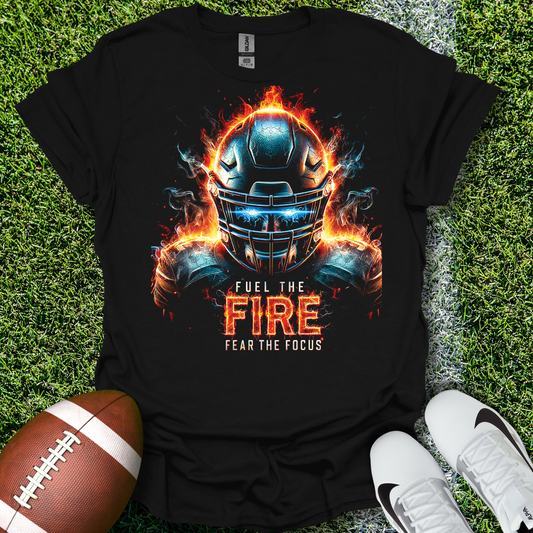Black t-shirt with a football helmet design and text on grass with a football and shoes.