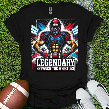 Black t-shirt with football player graphic and text 'Be Legendary Between the Whistles' on grass with a football and shoes.
