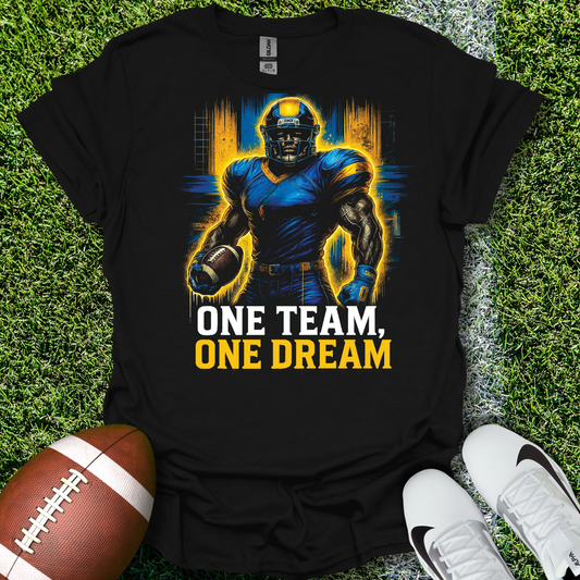 Black t-shirt with football player graphic and 'One Team, One Dream' text on grass with football and shoes.
