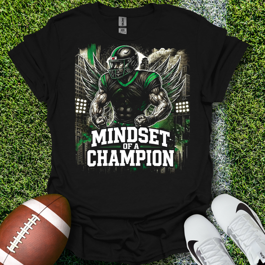 Black t-shirt with 'Mindset of a Champion' graphic on grass with football and shoes.