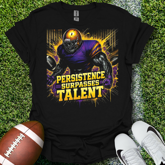 Black t-shirt with football player graphic and 'Persistence Surpasses Talent' text on grass with football and shoes.