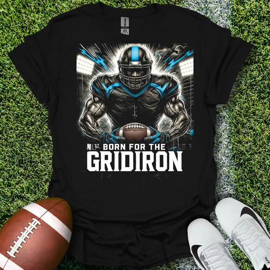 Black t-shirt with football player graphic and 'Born for the Gridiron' text on grass with a football and shoes.
