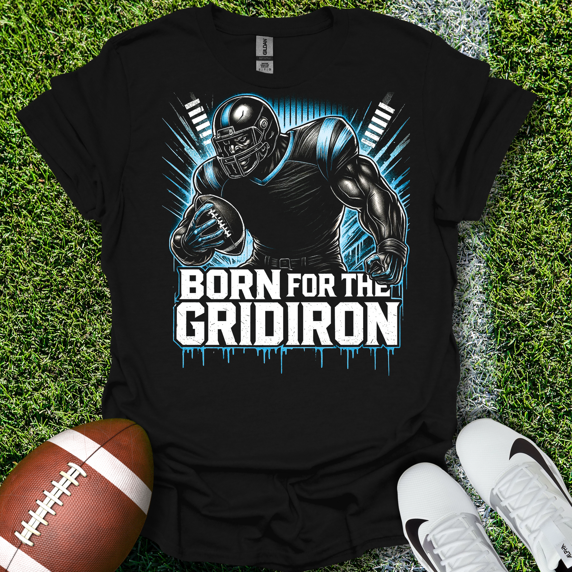 Black t-shirt with football player graphic and 'Born for the Gridiron' text on grass with a football and shoes.