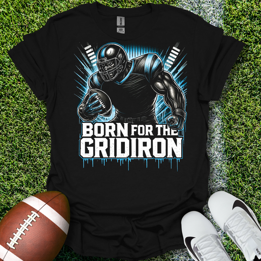 Black t-shirt with football player graphic and 'Born for the Gridiron' text on grass with a football and shoes.