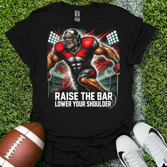 Black t-shirt with a football player graphic and text on grass with a football and shoes.